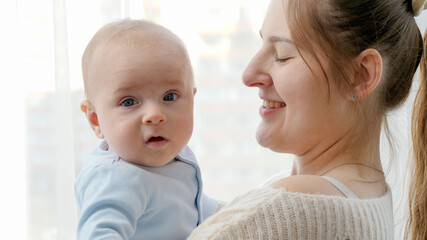 Cute little baby boy hugging mother and smiling in camera. Concept of family happiness and child development