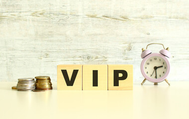 There are three wooden cubes with letters on the table next to the coins. The word VIP. On a gray background.