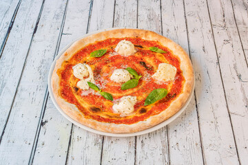 Margarita pizza for breakfast with gratin buffalo cheese balls, tomato and basil leaves on white table