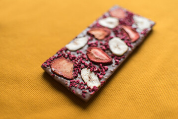 a bar of delicious milk chocolate with additions of dry raspberries and banana chips in place for the text in a bright yellow color