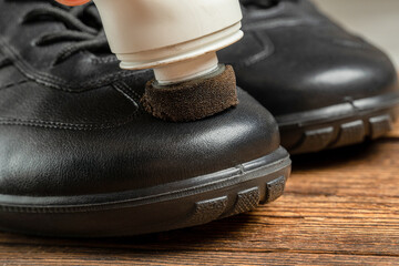 cleaning, polishing, restoration black leather boots with sponge brush and footwear care product, shoe polish