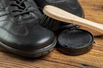 leather boots, brushes, shoe polish wax, footwear care products on wooden background