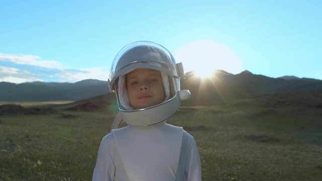 Little young happy child boy wearing astronaut uniform and helmet cosmonaut walking in sunset field nature. Space man, Kid big dream flying, childhood, freedom, travel, future, professions concept