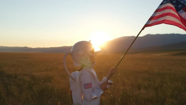 Little young happy child boy wearing astronaut uniform and helmet cosmonaut showing american flag of United States. Space man, Kid dream flying, childhood, freedom, travel, future, professions concept