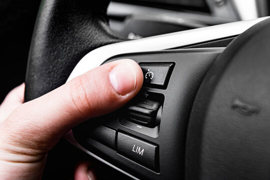 Hand Pushes Cruise Control Button On Steering Wheel.