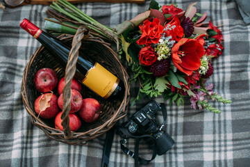 Still life. Basket with flowers, fruits and a bottle of wine on a blanket. Dinner with alcohol in...