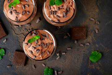 Vegan chocolate mousse with mint, bar of chocolate and cocoa beans on a dark background.
