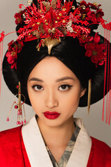 Portrait of japanese woman with national hairdo looking at camera isolated on grey