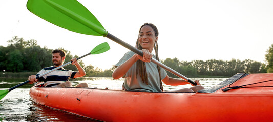 Happy young couple of friends having fun on kayak on a late summer afternoon - obrazy, fototapety, plakaty