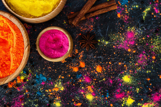 Holi festival celebration. Traditional Indian colorful holi powder decoration. Top view of organic gulal colors, dry paints in wooden bowls, spices, herbs on concrete background. Happy holiday. © Monstar Studio
