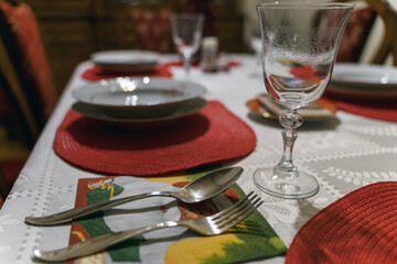 Festive Christmas decoration of the dinner table. Beautiful white and red clothes and napkins, plate empty wine glass cup cutlery. Santa Claus in a red coat