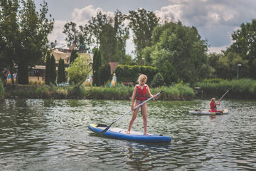 brave child balancing on paddle board enjoying fun and adrenaline on pond