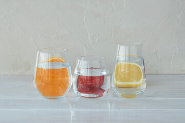 Cutted orange, lemon and strawberry behind transparent glasses with water, ditortion, optical...
