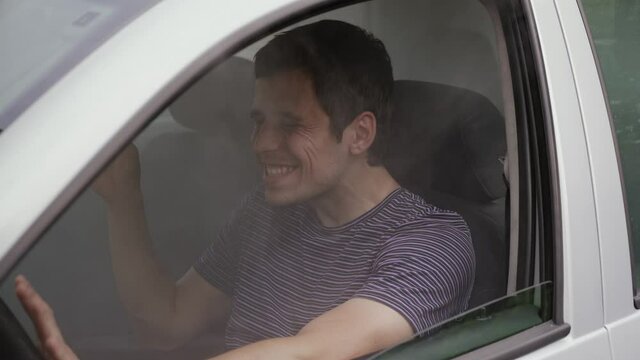 Cheerful man smokes weed while driving a car
