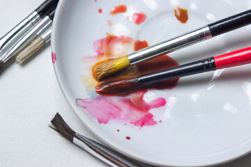 Paint brushes in paint on a white background. Artist's tools. Mixing paints