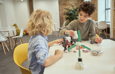 Busy little boys examining robots, sitting at the table during STEM class