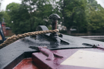 Close up of rope tied around a cleat on the front of a narrowboat moored on Regent's Canal, London,...