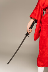 Cropped view of woman in oriental kimono holding sword isolated on grey