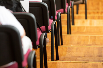 Rows of empty chairs along the wooden parquet steps in the business presentation hall.