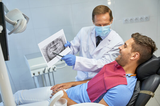 Qualified dentist and his young patient discussing x-ray image