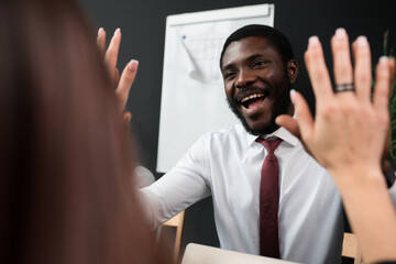 Fototapeta premium Happy african american businessman in shirt smiling and giving five to woman