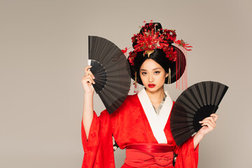 Asian woman in kimono holding black fans isolated on grey - Powered by Adobe