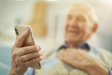 Fototapeta na wymiar Smiling elderly man using mobile phone at home