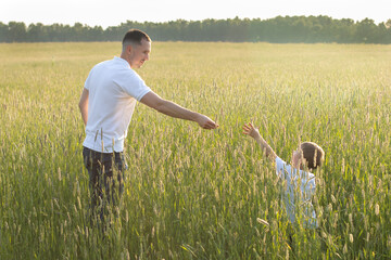 Father and son in a field at sunset. The father holds out his hand to his son. Happy family...