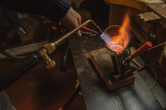 Crop jeweler melting metal with torch