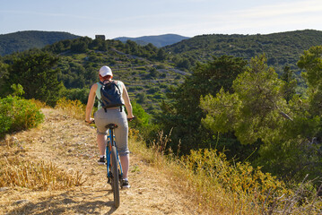 A woman cyclist rides along a mountain path on her mountain bike on a summer sunny day. activity. extreme sport