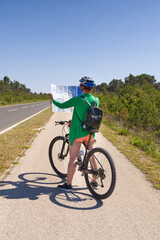 Fototapeta na wymiar tourist, happy woman in a helmet on a bicycle examining a map at the intersection of bicycle roads. concept of outdoor activities or cycling travel in sunny day
