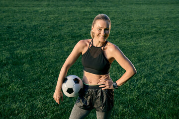 Active lifestyle. Sporty beautiful middle aged woman, football player smiling at camera and holding...