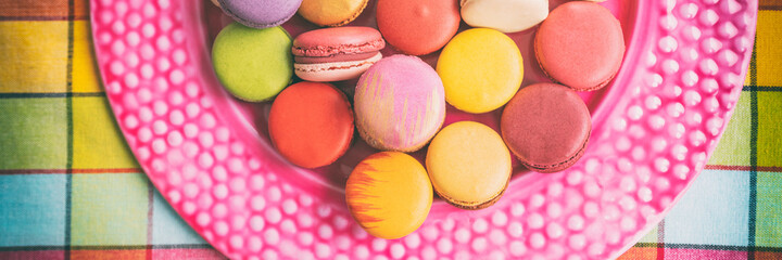 Many macarons at bakery in gift box. Panoramic banner of french sweet desserts top view.