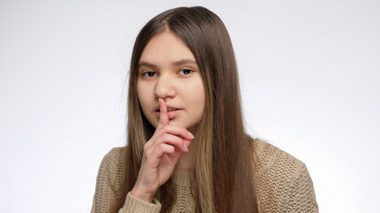 Cute smiling girl holding finger at mouth in shhh gesture after telling secret