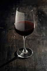 full wine glass on wooden table with side light.