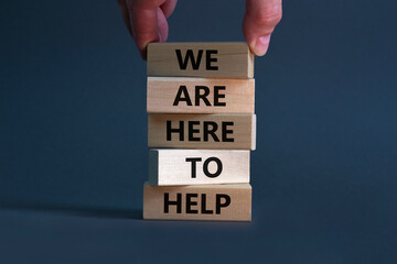 Support and help symbol. Wooden blocks with words 'we are here to help'. Businessman hand. Beautiful grey background, copy space. Business, help and support concept.