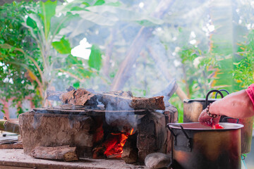 A woman cooks on a wood stove with soot filled pots around