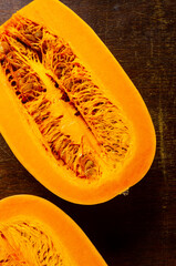 Cutted fresh orange big pumpkin on wooden background, close up. Organic agricultural product, ingredients for cooking, healthy food vegan.