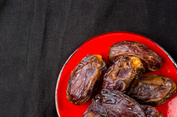 Big luxury dried date fruit in bowls on the dark surface, kurma ramadan kareem concept, close up.