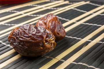 Big luxury dried date fruit on the bamboo mat, kurma ramadan kareem concept, close up.