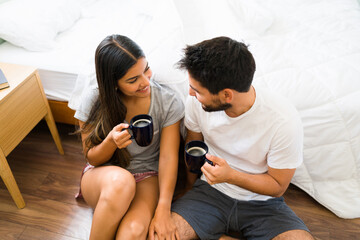 Boyfriend bringing coffee to his girlfriend in the bedroom