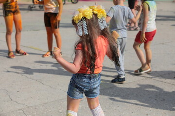Happy little girl dancing on the street in the schoolyard. Many children relax on vacation outside...