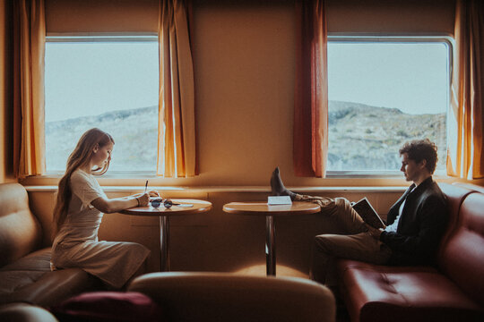 Focused couple reading book and writing notes while riding ferry