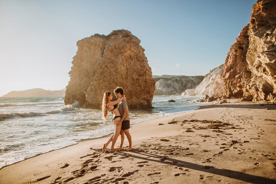 Young couple hugging on sunny rocky seacoast