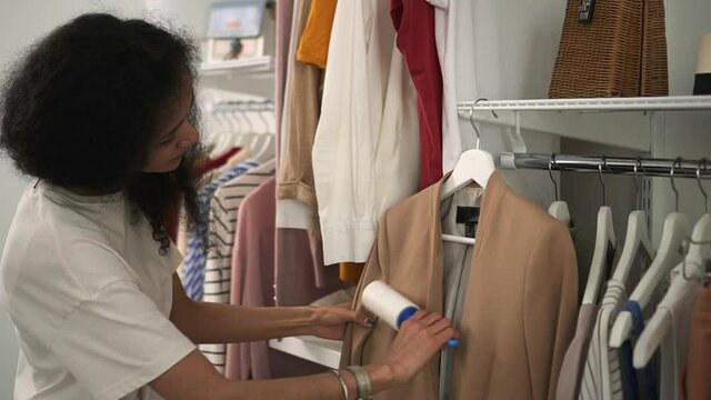 Taking care of clothes lady cleans coat with lint roller Spbd