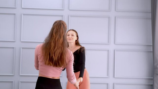 Beautiful woman free style dancing with female instructor. warm up exercise activity. Duo dancers joyful women wearing leggings and tops having fun while rehearsing dance in performance spacious studi