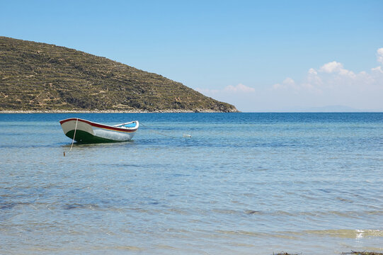 Single boat moored on the seashore with the mountain in the background. Concept of calm and stillness.