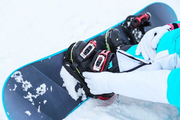 snowboarder puts on a snowboard close up. snowboard boot bindings close up