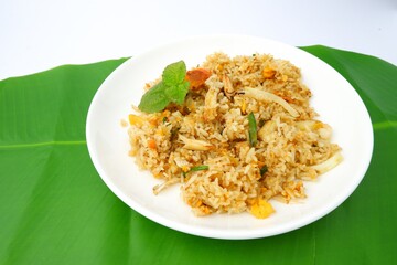 Delicious crab fried rice on a white plate on a green leaf background.Thai food.