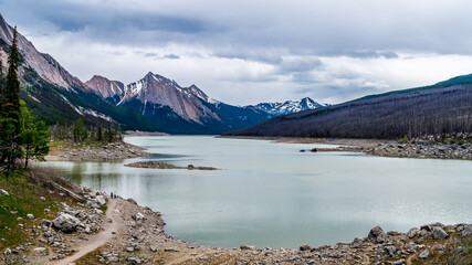 Fototapeta na wymiar Medicine Lake in Jasper National Park in the Canadian Rockies under Dark Clouds. The lake fills and empties annually as the water drains through an underground drainage system